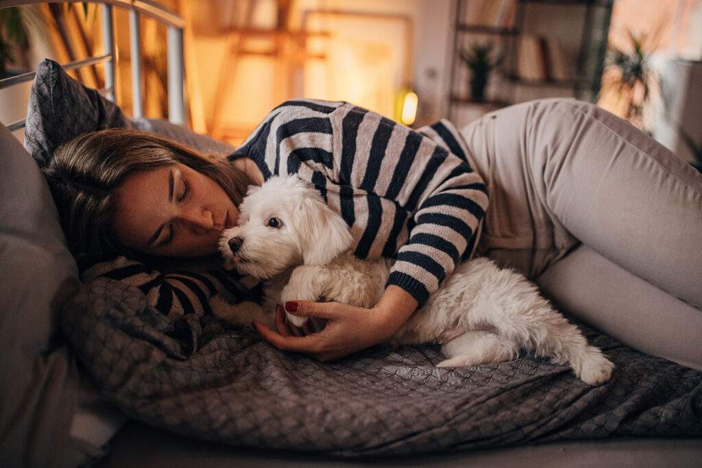Woman relaxing in bed with puppy